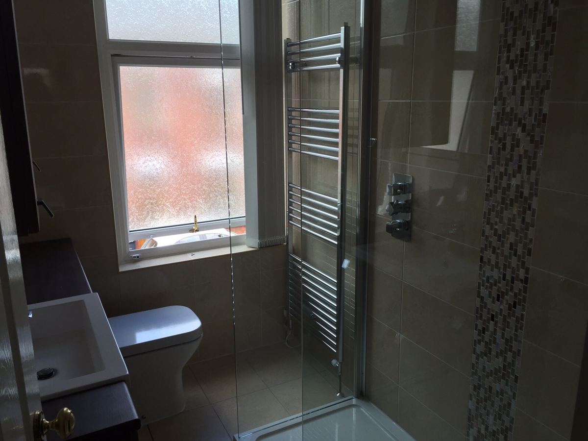 Shower room with glass enclosure and mosaic tile strip