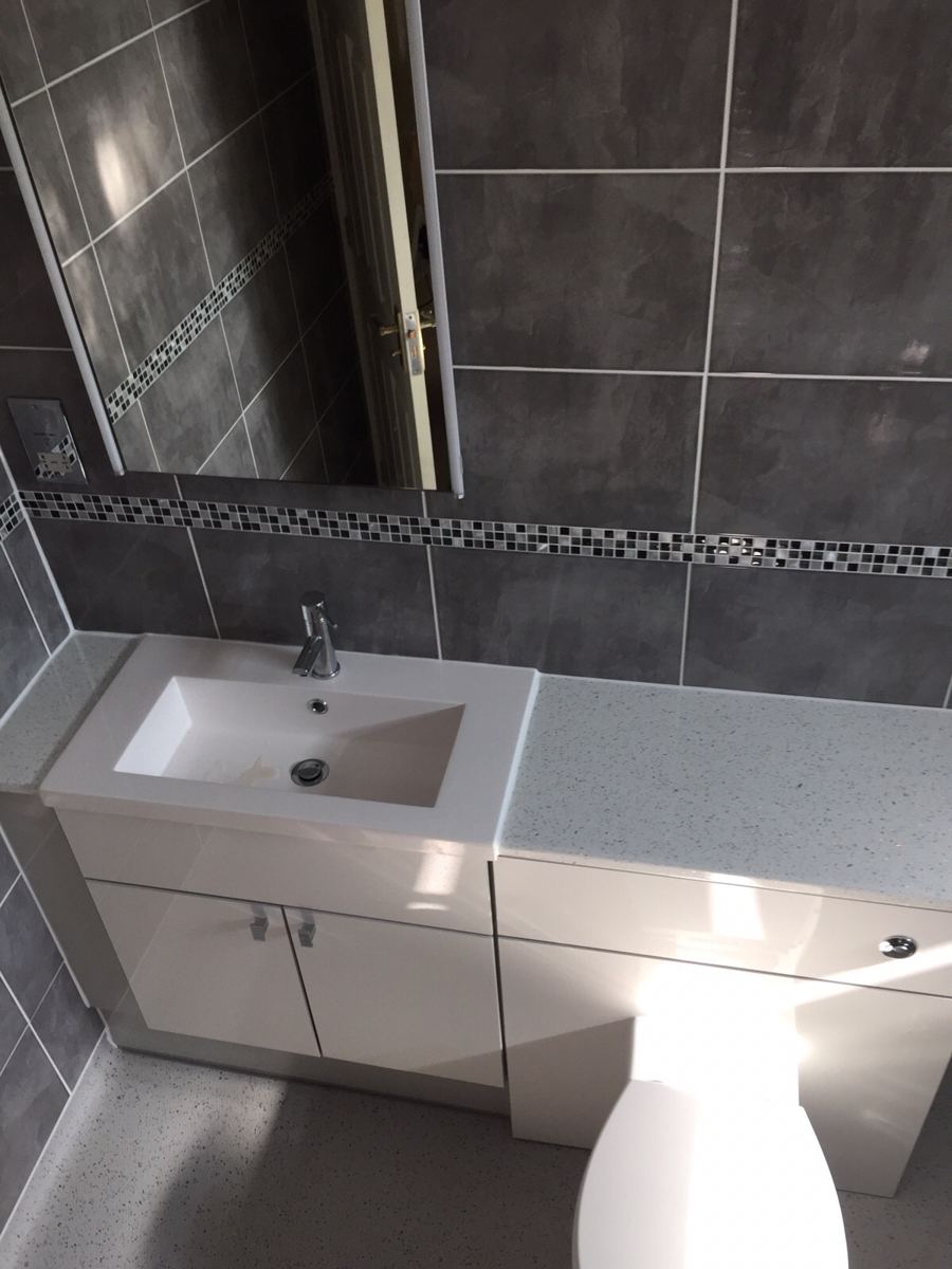 Grey bathroom with white fitted vanity and toilet unit