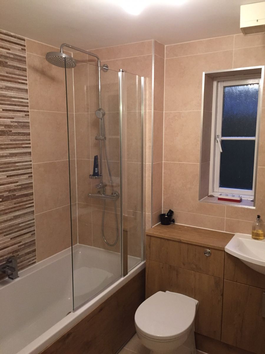 Bath with glass screen, overhead shower and fitted furniture